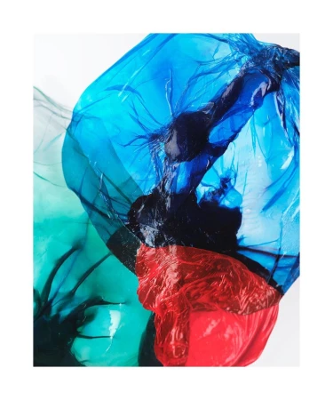 Abstract image featuring translucent overlapping plastic sheets in vibrant blue, red, and green colors against a bright white background.