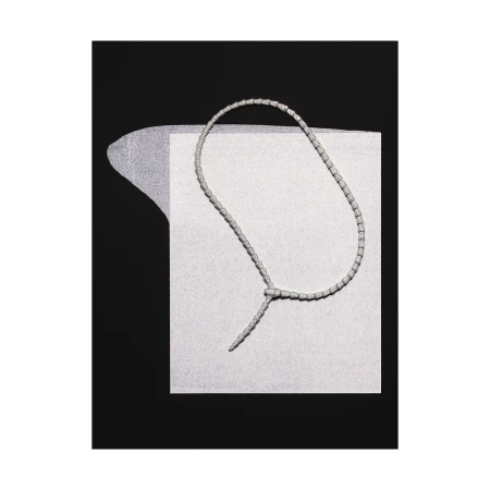 Elegant necklace made of white beads knotted on a textured paper background, against a solid black backdrop, jewelry product shot.