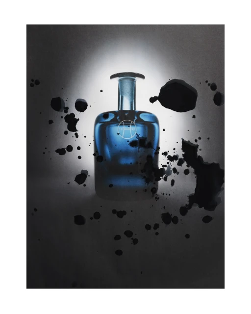 Studio shot of a blue glass perfume bottle with an abstract logo, surrounded by dark ink splashes against a white and grey gradient background.