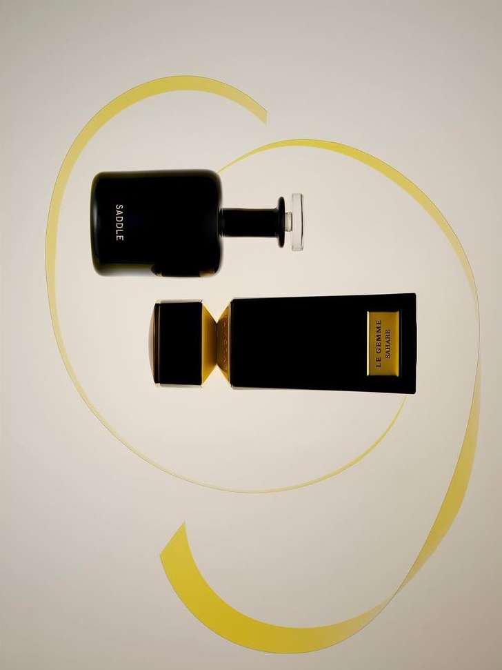 Black and gold perfume bottles on a light surface with a yellow ribbon creating an elegant presentation.