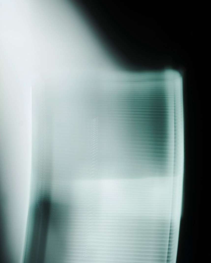Abstract image featuring blurry white and teal light on a black backdrop, creating a modern and ethereal visual effect.