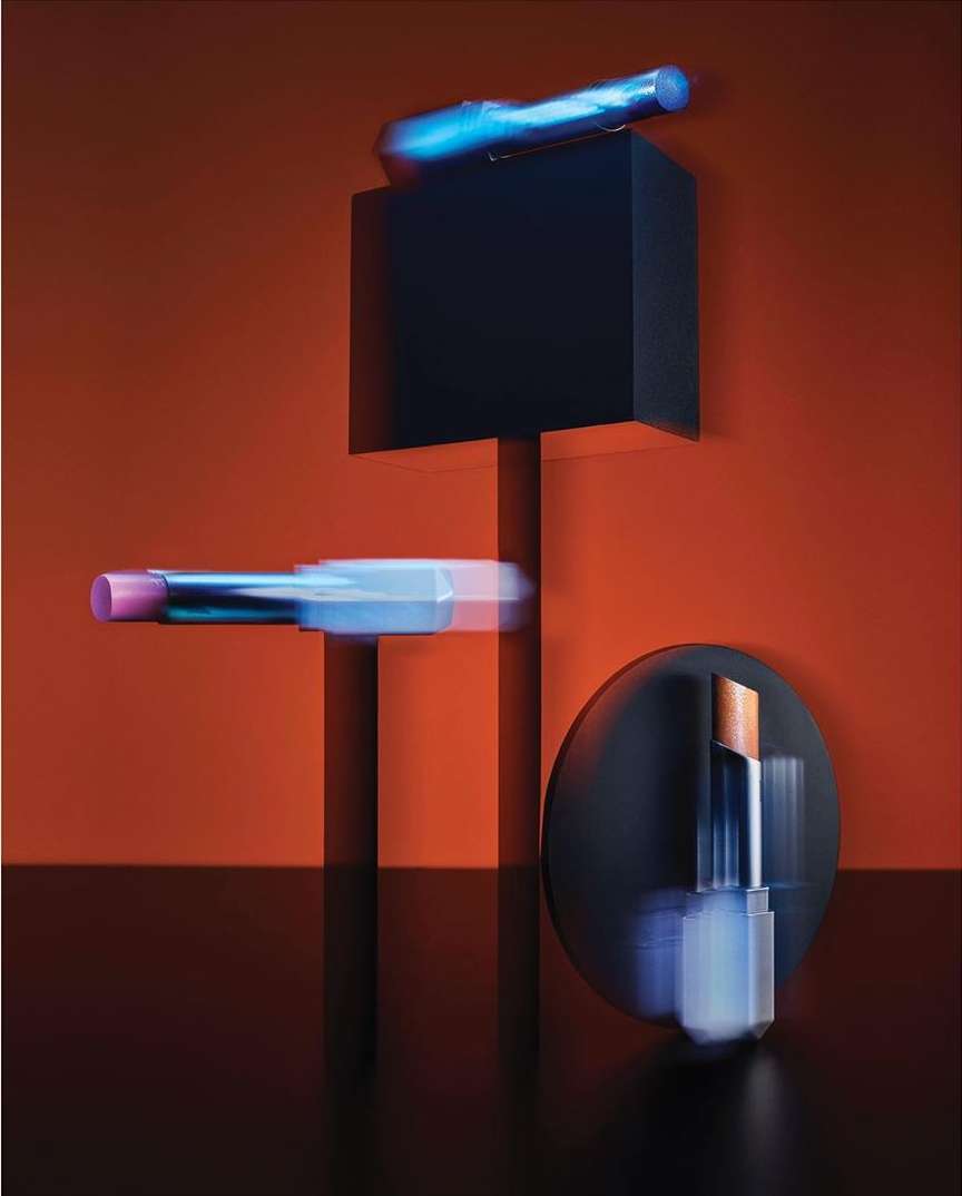 Abstract still life featuring lipstick tubes in a studio setting against a red background, showcasing beauty and cosmetic products.