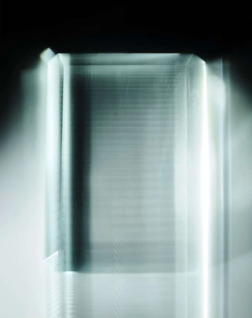 Abstract photograph featuring a blurry, translucent glass-like geometric shape with soft, glowing light against a dark, contrasting backdrop.