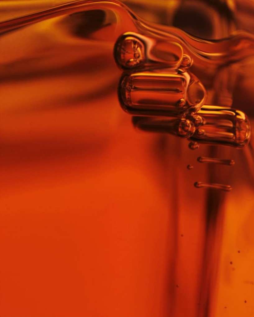 Macro shot of golden liquid with suspended bubbles. Abstract food or beverage product photography, liquid, viscous material, and golden hue.