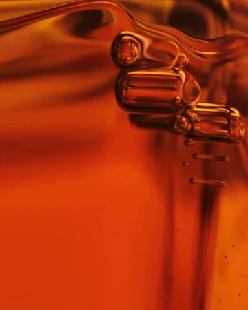 Macro shot of golden liquid with suspended bubbles. Abstract food or beverage product photography, liquid, viscous material, and golden hue.