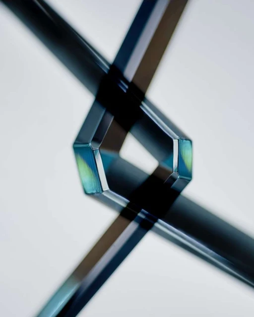 Abstract image of intersecting translucent tubes creating geometric shapes and sharp shadows against a plain light backdrop. 