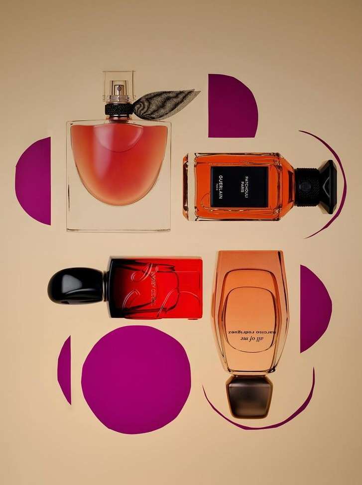 Four perfume bottles are arranged on a pale yellow background with geometric purple accents, showcasing a modern, minimalist aesthetic.