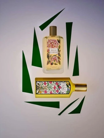 Two Gucci Flora perfumes, one rectangular and one cylindrical, presented on a pale background with geometric green paper shapes.