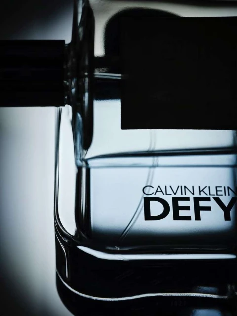 Close-up of a Calvin Klein Defy fragrance bottle featuring clear glass and black accents, showcasing a minimalist and modern aesthetic.
