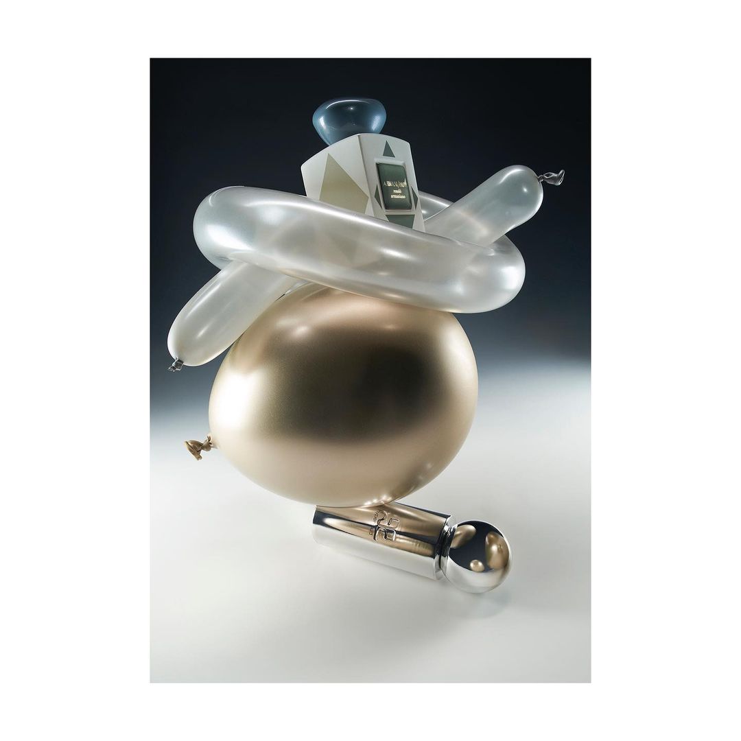 Still life with golden and silver balloons, and an abstract geometric form with a monitor, creating a surreal, unique composition.