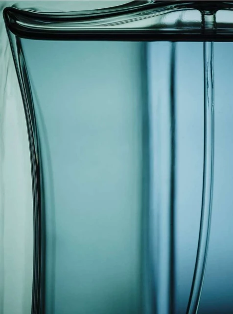 Close-up of a transparent blue glass object with a curved shape, showcasing its form and the light reflecting through the material.