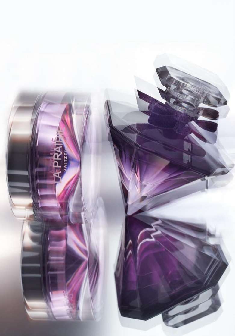 Elevated view of skincare product and perfume bottle by La Prairie with white backdrop. Focus on luxury brand. Minimalist studio shot.