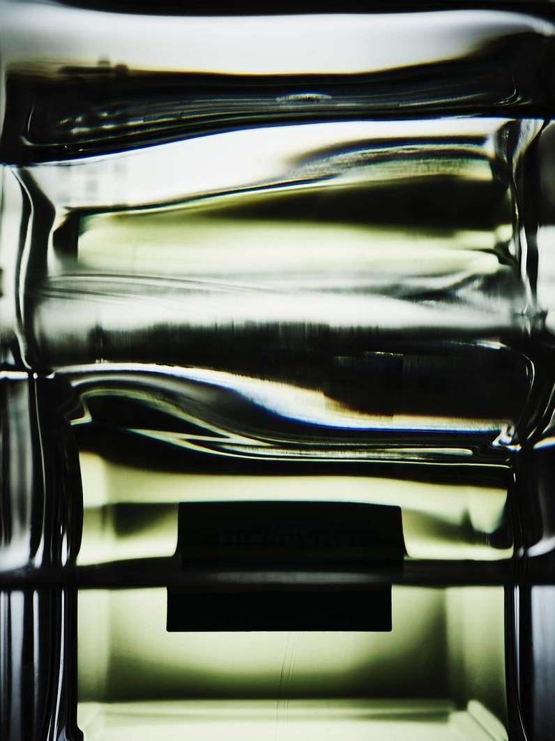 Abstract close-up of a clear, textured glass object with dark horizontal bands, highlighting its shape and form.