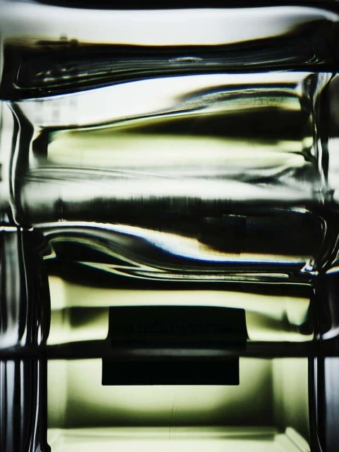 Abstract close-up of a clear, textured glass object with dark horizontal bands, highlighting its shape and form.
