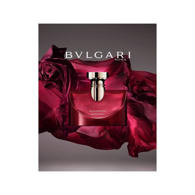 Elegant still life of Bulgari's 'Magnolia Sensuel' perfume bottle against a draped burgundy fabric, capturing luxury and sophistication.