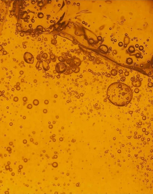 Abstract close-up of amber liquid with bubbles, creating a textured and visually interesting surface. Ideal for backgrounds or textures.