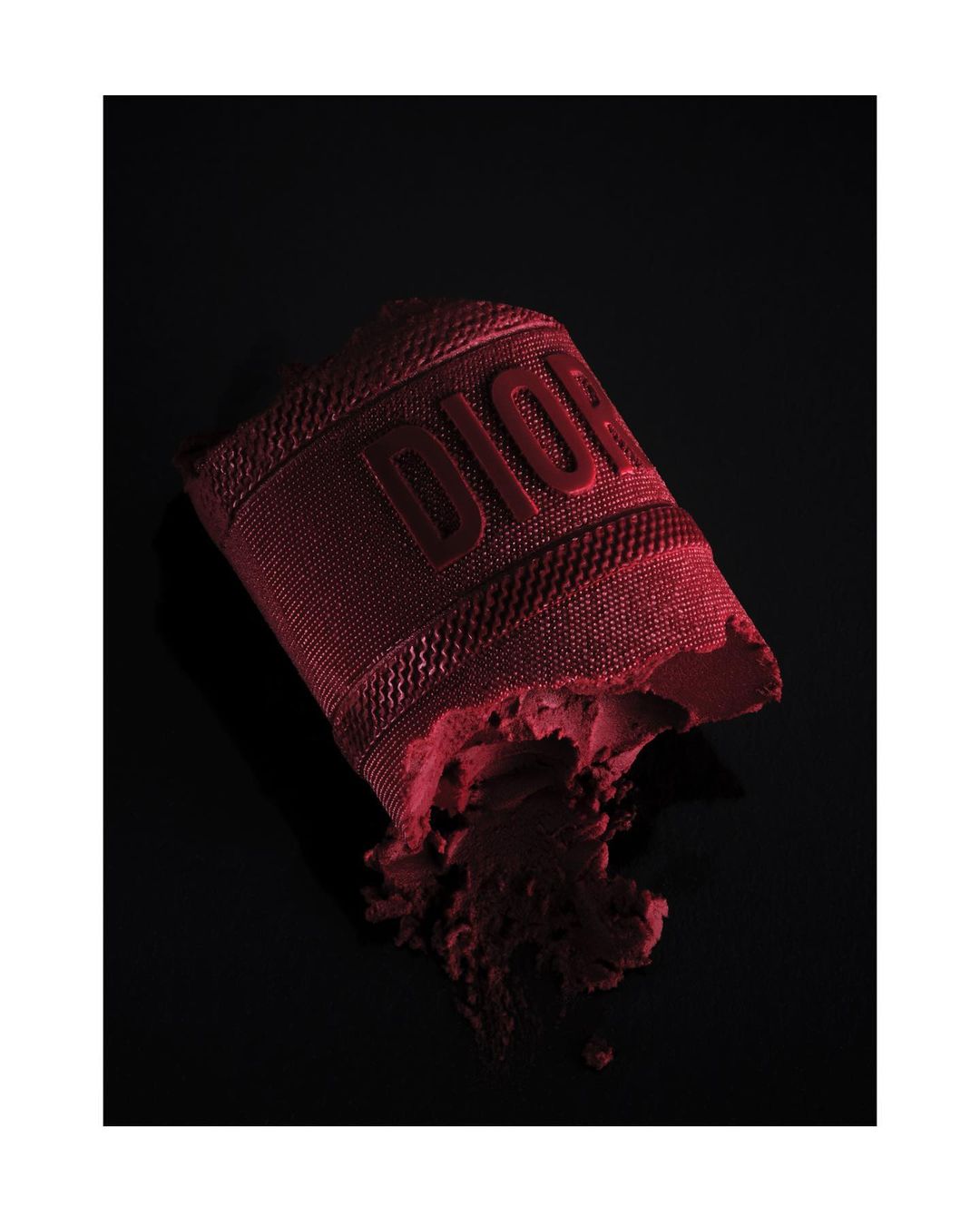 Burgundy Dior makeup product with raised logo on a black backdrop, beauty and fashion photography. Cosmetic still life image.