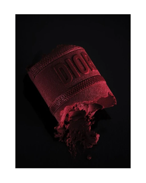 Burgundy Dior makeup product with raised logo on a black backdrop, beauty and fashion photography. Cosmetic still life image.