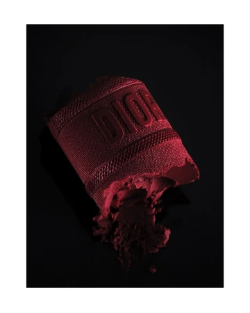 Burgundy Dior makeup product with raised logo on a black backdrop, beauty and fashion photography. Cosmetic still life image.