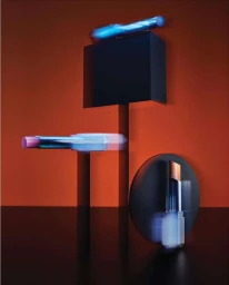Commercial still life featuring lipsticks displayed with motion blur on geometric props against an orange and black backdrop.
