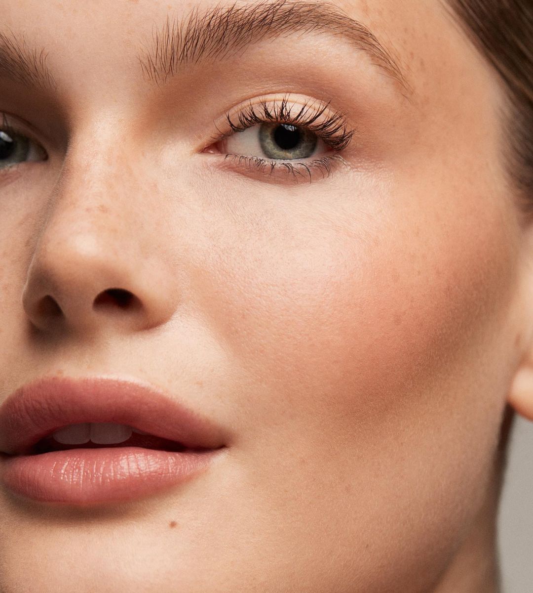 Close-up portrait of a woman's face with fair skin, showcasing natural makeup and soft, diffused lighting in a beauty context.