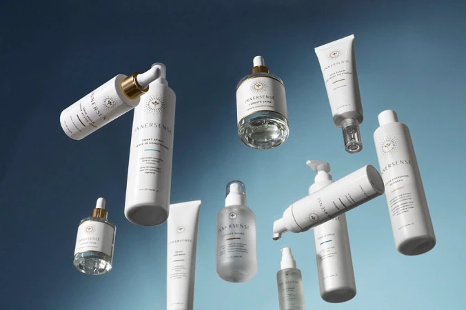 Still life of Innersense Organic Beauty haircare products, including shampoos, conditioners, and styling aids against a blue gradient background.