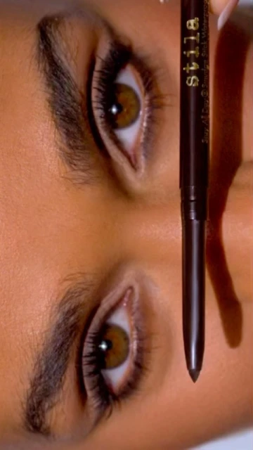 Close-up of a woman's face with a Stila eyeliner pencil, focusing on the model's eyes and the cosmetics used to enhance her features.
