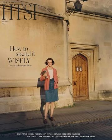 A woman standing outside an old stone building holding a book, wearing a pink blazer, denim skirt, and loafers.