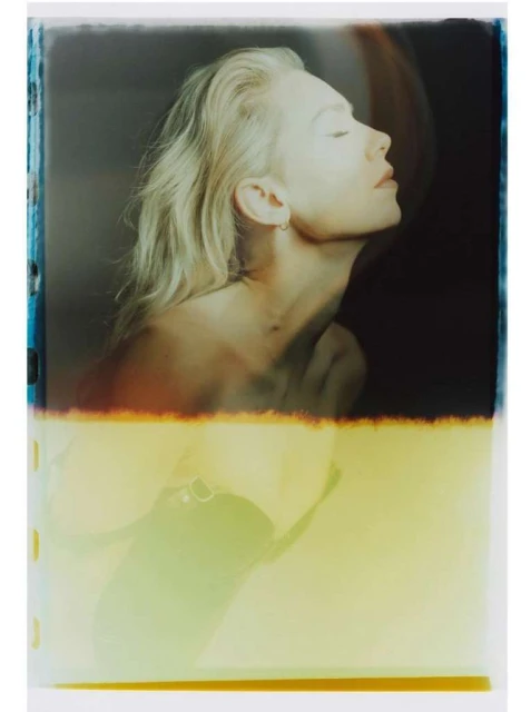 Artistic portrait of a fair-skinned woman with blonde hair and closed eyes in a photo studio with light and color gradients.