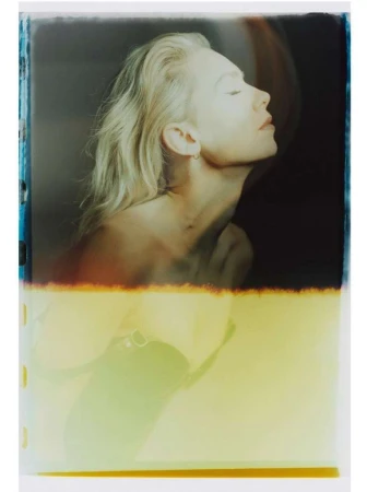 Artistic portrait of a fair-skinned woman with blonde hair and closed eyes in a photo studio with light and color gradients.