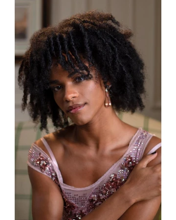 Portrait of a woman with dark coiled hair wearing an embellished pink dress with sequin details photographed by Tom Ivin