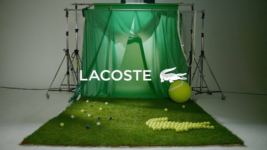 Promotional shot of Lacoste logo and crocodile made from tennis balls on green turf, set against a green screen in a photo studio.