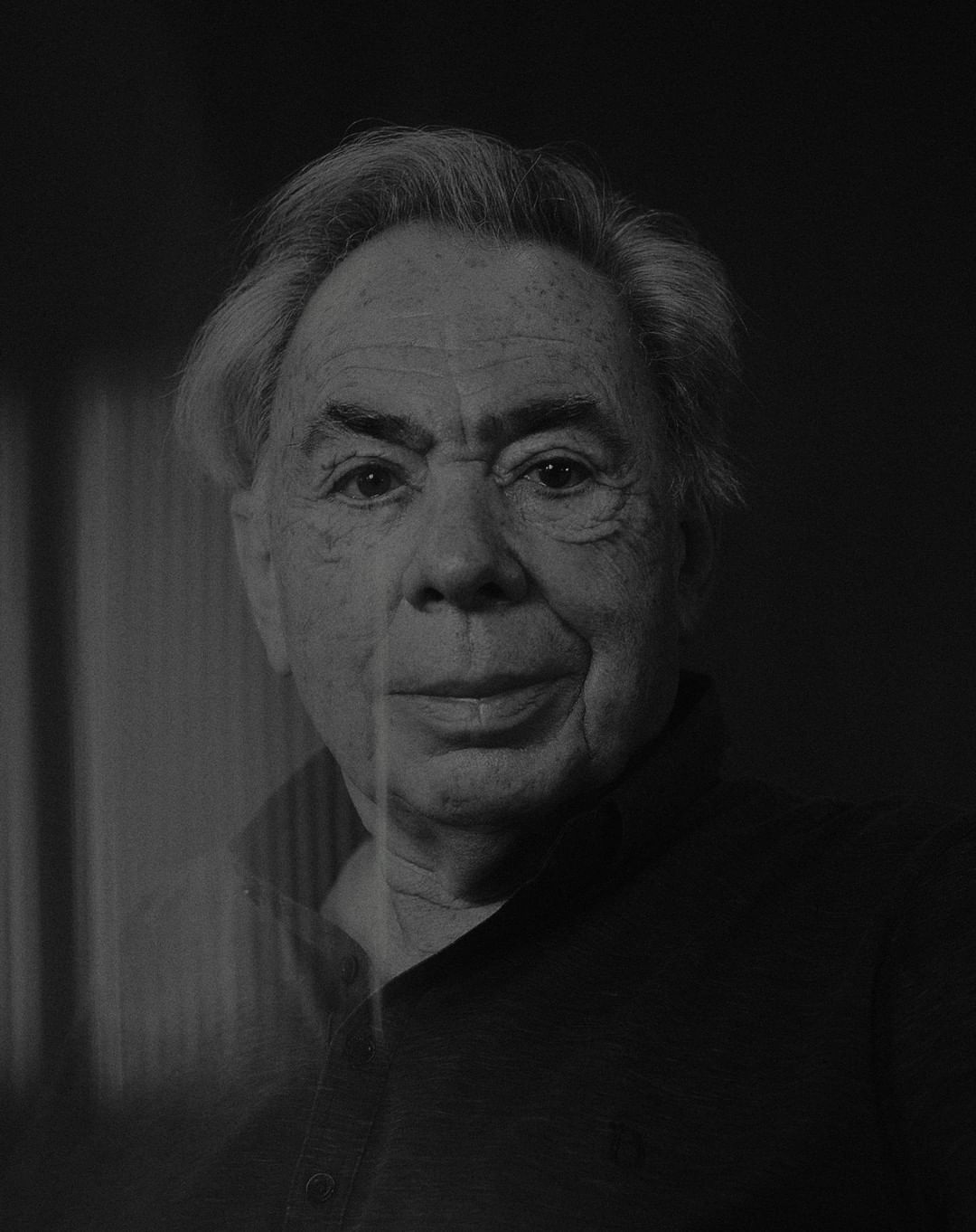 Black and white portrait of an elderly man with light hair and a collared shirt against a dark background.