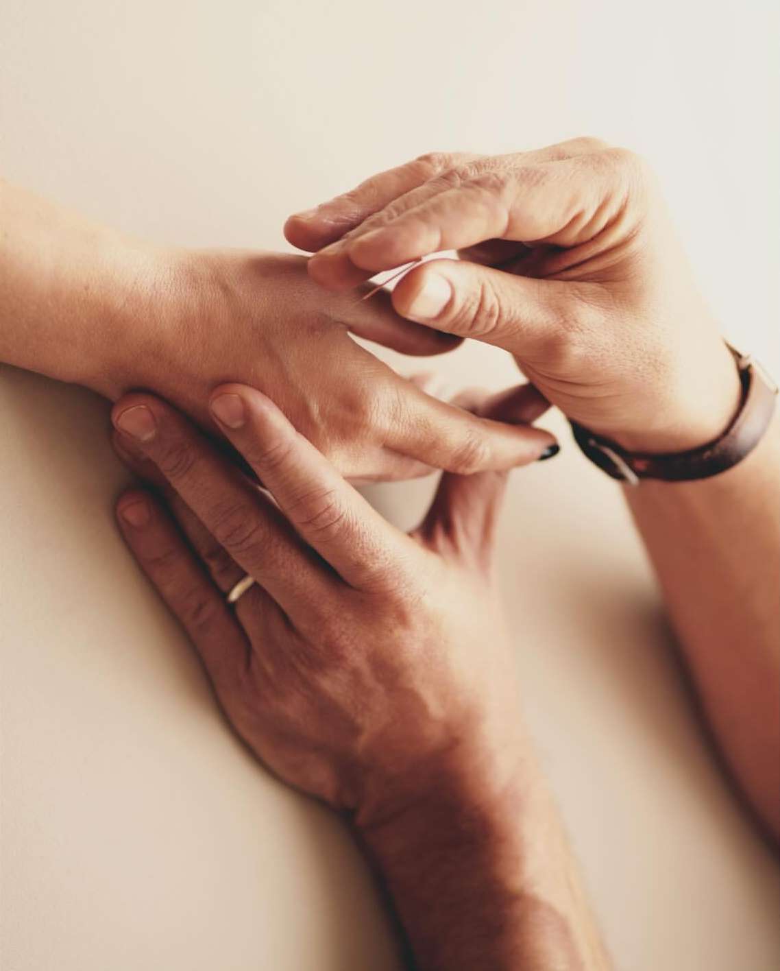 Close-up shot of a person applying a bandage to another person's hand indoors, showcasing care and attention to detail.