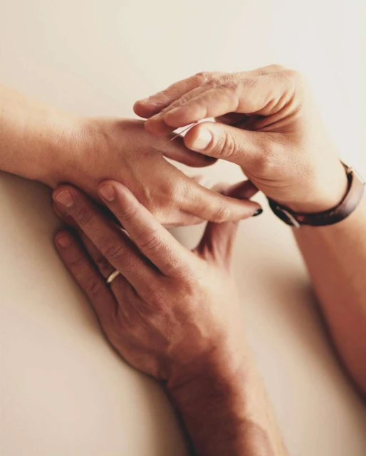 Close-up shot of a person applying a bandage to another person's hand indoors, showcasing care and attention to detail.