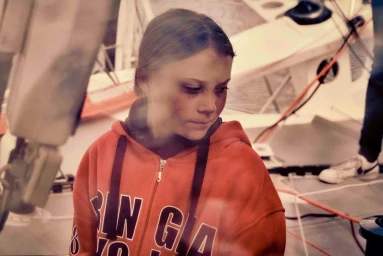 Greta Thunberg wearing an orange zipped hoodie on a boat, photographed by Tom Jamieson in New York.