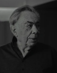 Monochrome portrait of an elderly man with grey hair wearing a dark button-down shirt, captured by Tom Jamieson.