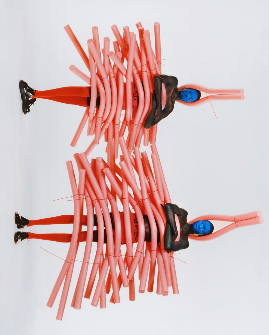 Conceptual image with two abstract figures constructed from pink foam tubes and black and blue clay on a white backdrop.