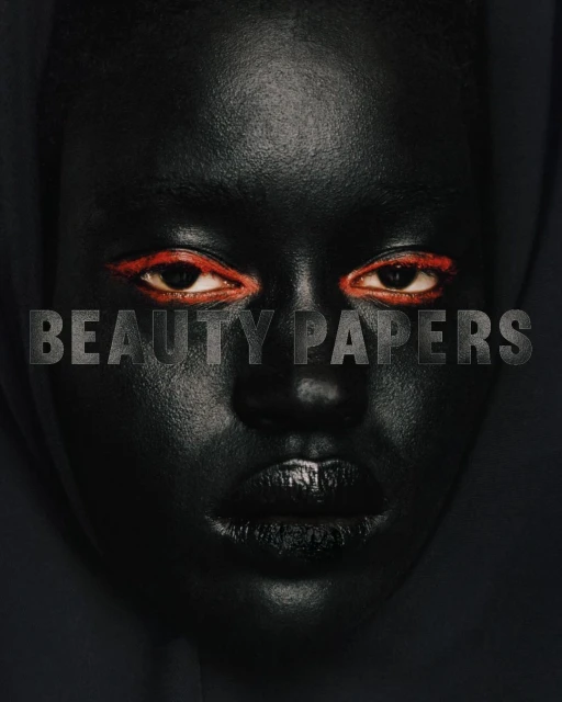Close-up portrait of a dark-skinned woman with vibrant red eyeliner, black lipstick, and 'BEAUTY PAPERS' text overlayed.