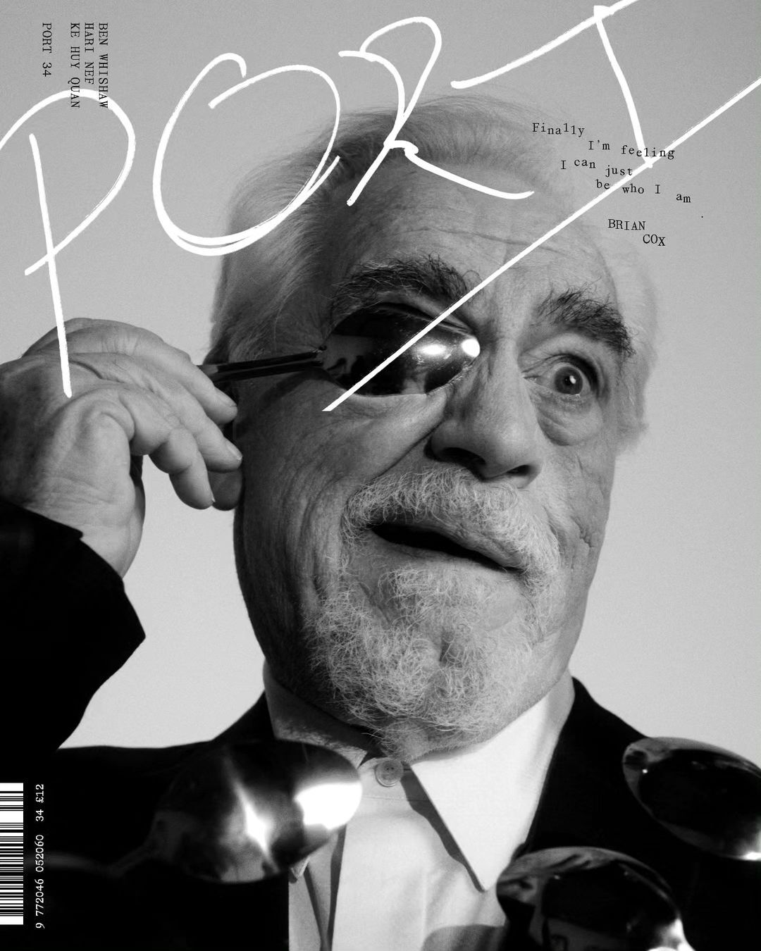 Black and white magazine cover featuring Brian Cox wearing spoons on his face and eye with large white title text and barcode.