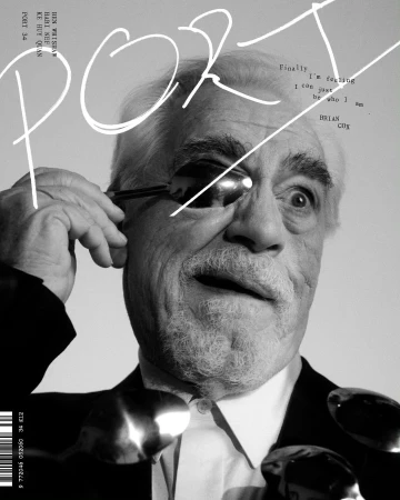 Black and white magazine cover featuring Brian Cox wearing spoons on his face and eye with large white title text and barcode.
