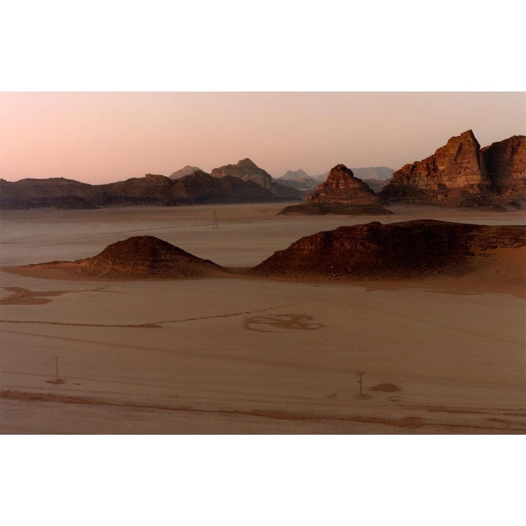 Panoramic view of a vast desert landscape featuring rock formations and a light pink sky, showcasing the beauty of nature.