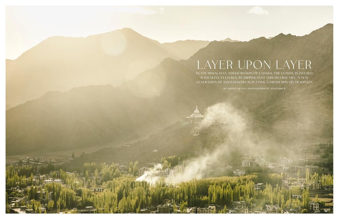 Scenic landscape photography of a village nestled in a valley surrounded by mountains with sunlight and mist creating an ethereal effect.