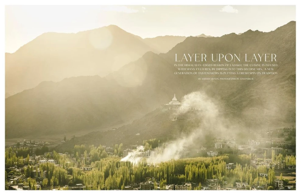 Scenic landscape photography of a village nestled in a valley surrounded by mountains with sunlight and mist creating an ethereal effect.