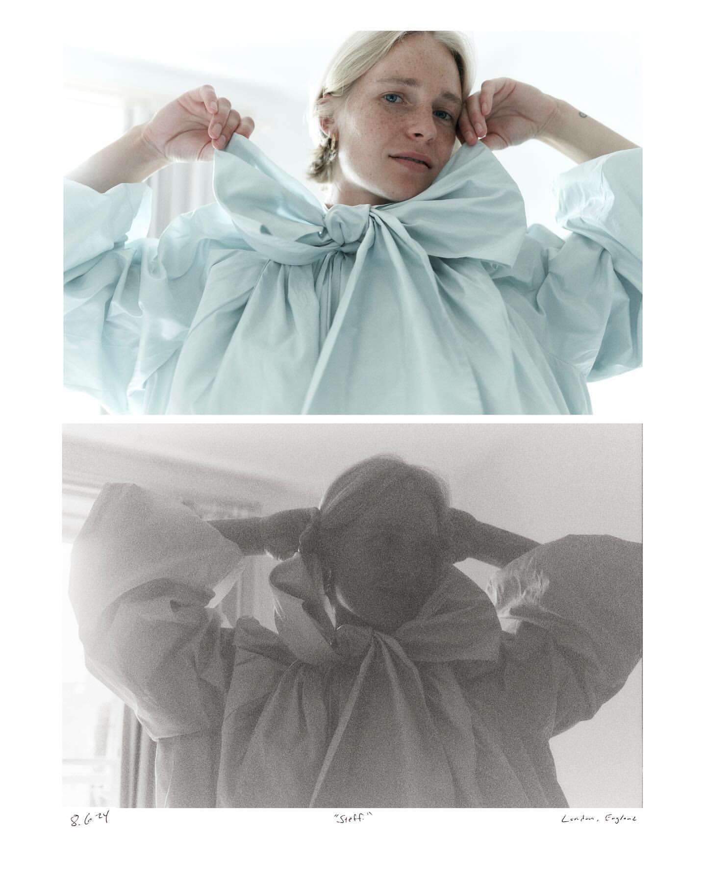 Portrait of a fair-skinned adult female with blonde hair wearing a large pale blue bow dress with a blurred black and white image underneath.