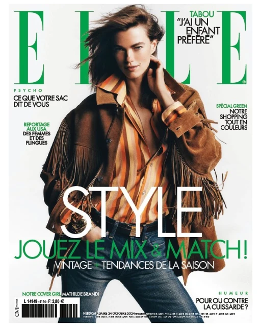 Elle magazine cover featuring a female model with windswept hair, wearing a striped shirt and fringed jacket, against a light background.