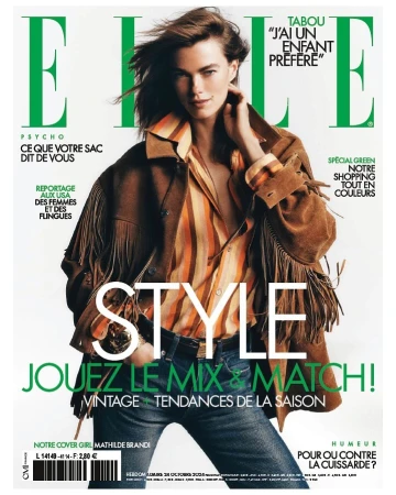 Elle magazine cover featuring a female model with windswept hair, wearing a striped shirt and fringed jacket, against a light background.