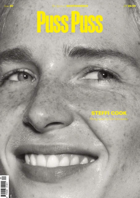 Close-up magazine cover photo of Steffi Cook in black and white with yellow title text 'Puss Puss'. Skin is visible with freckles.