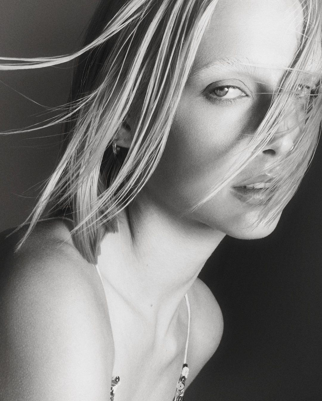 Close up portrait of a blonde woman with hair blowing across her face photographed by Tom Schirmacher