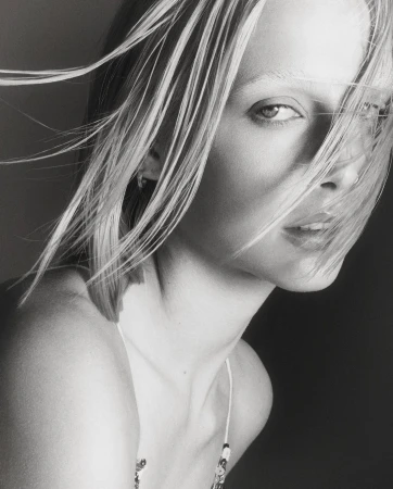 Close up portrait of a blonde woman with hair blowing across her face photographed by Tom Schirmacher
